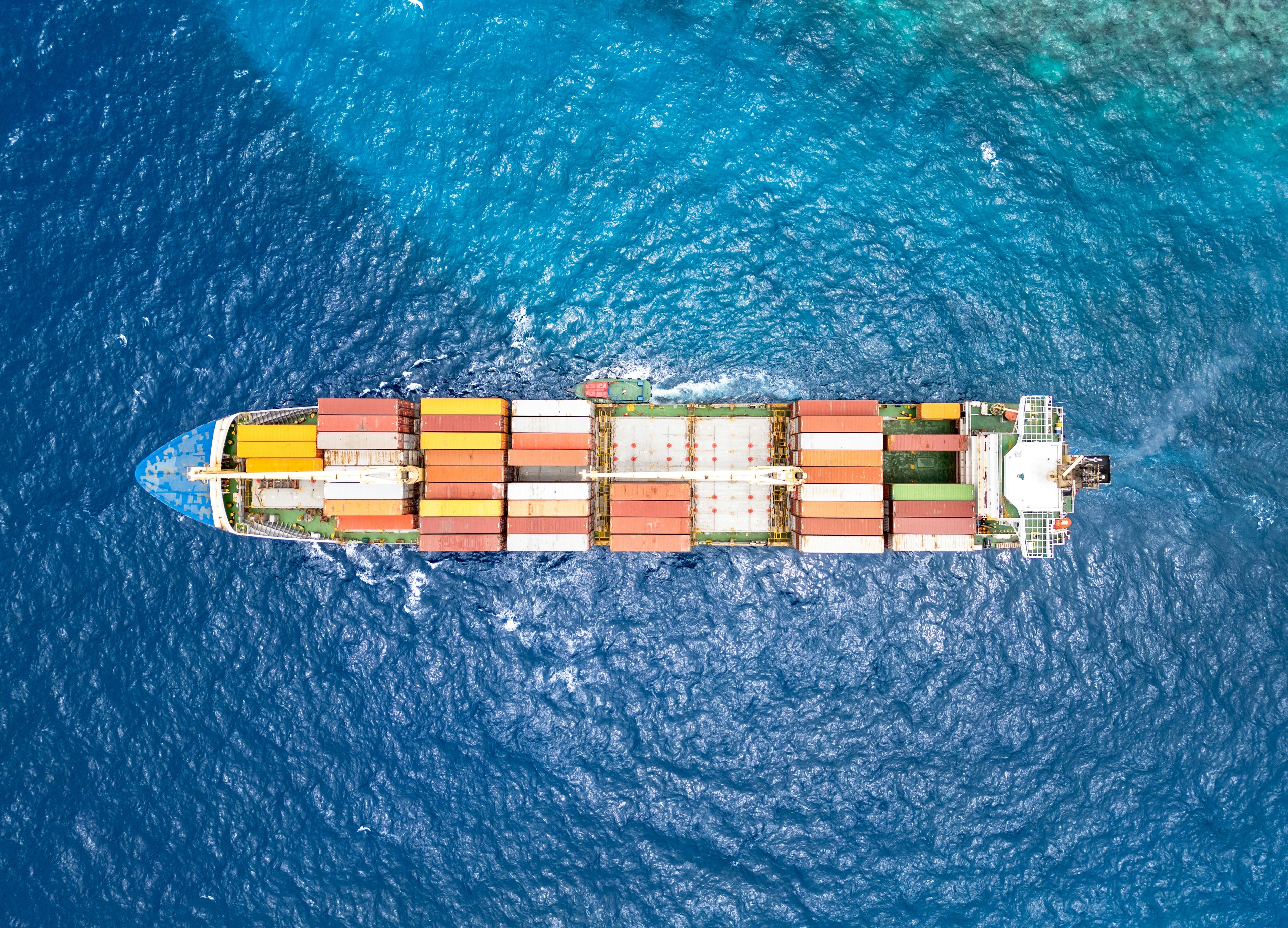 Container ship under way, its wake trailing across the deep-blue sea.